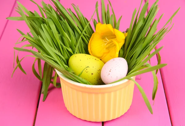 Påskägg i skål med gräs på rosa träbord närbild — Stockfoto