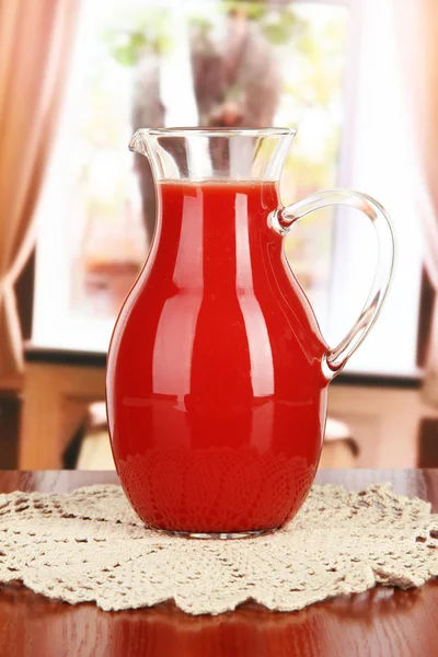 Tomato juice in pitcher on table in room — Stock Photo, Image