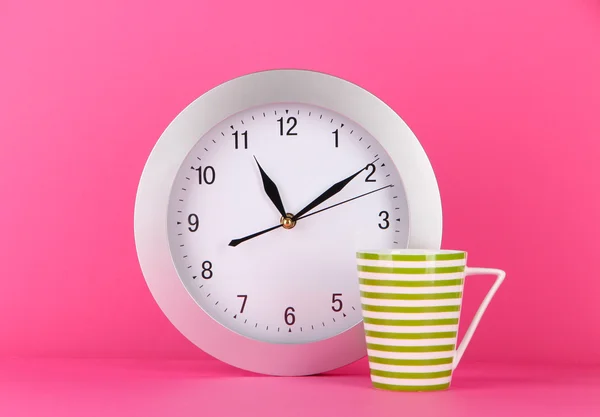 Cup tea and clock on pink background — Stock Photo, Image