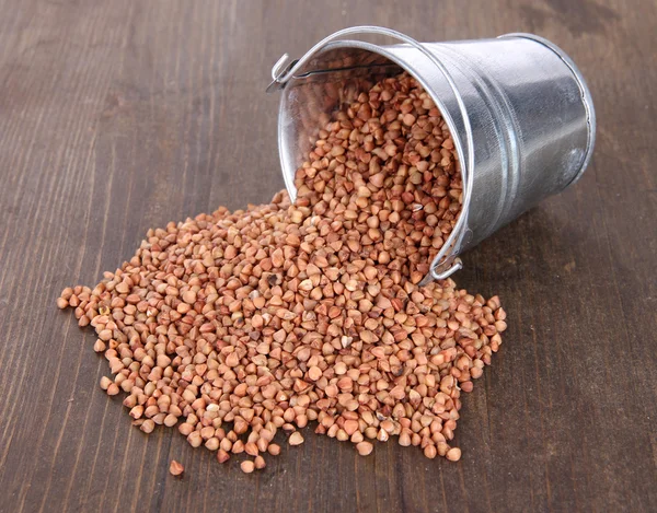 Overturned bucket with grains on wooden background — Stock Photo, Image