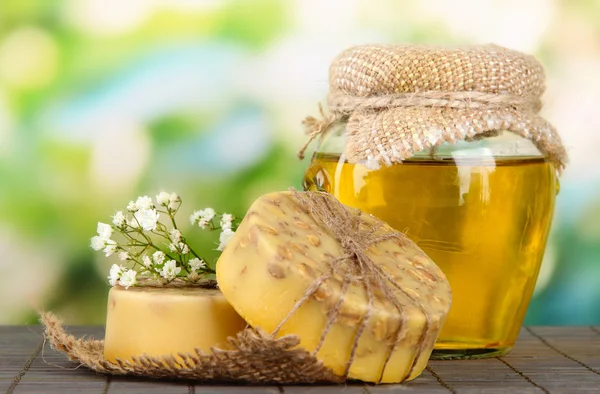 Hand made soap and ingredients for soap making on bamboo mat, on green background — Stock Photo, Image