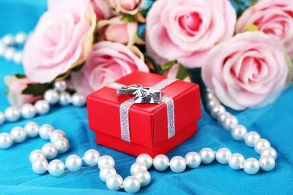 Роза и подарочная коробка на голубой ткани — стоковое фото