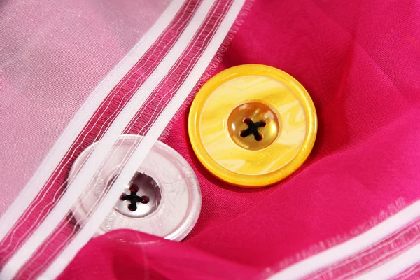 Две кнопки на розовой и белой ткани — стоковое фото