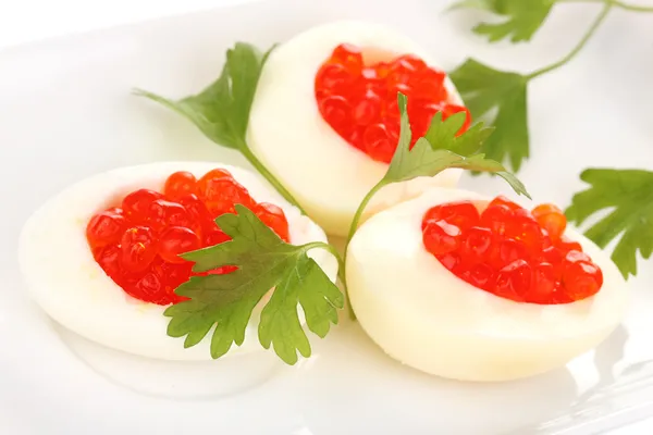 Красная икра в яйцах на белой тарелке крупным планом — стоковое фото
