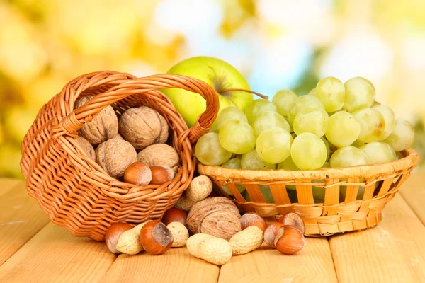 Виноград в кошику з горіхами на дерев'яному столі — стокове фото