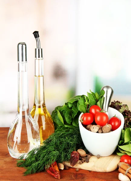 Composition of mortar, bottles with olive oil and vinegar, and green herbals, on bright background — Stock Photo, Image