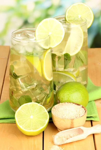 Glasses of cocktail with lime and mint on wooden table on bright background — Stock Photo, Image