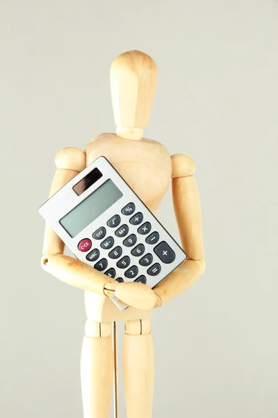 Wooden mannequin with calculator on grey background — Stock Photo, Image