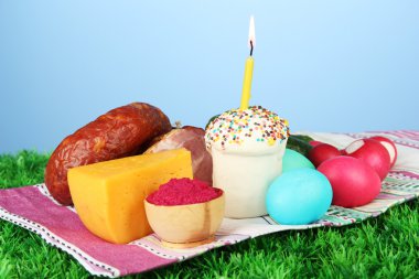 geleneksel Paskalya gıda mavi zemin üzerine yeşil çimenlerin üzerinde parlak havlu içinde kavramsal fotoğraf