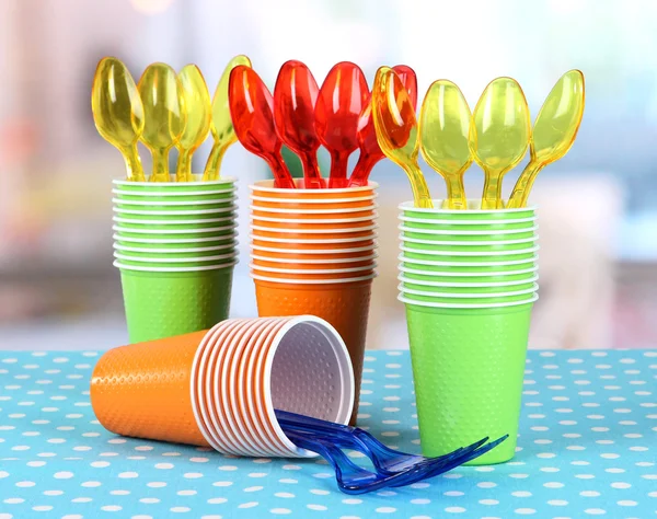 Cups, spoons and forks, of different colors on bright background — Stock Photo, Image