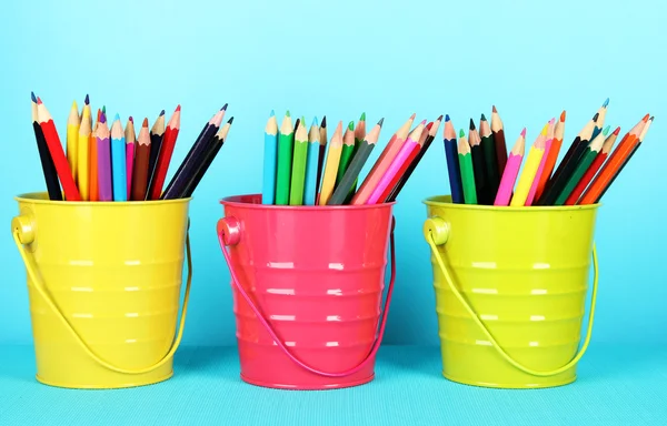 Lápis coloridos em três baldes sobre fundo azul — Fotografia de Stock