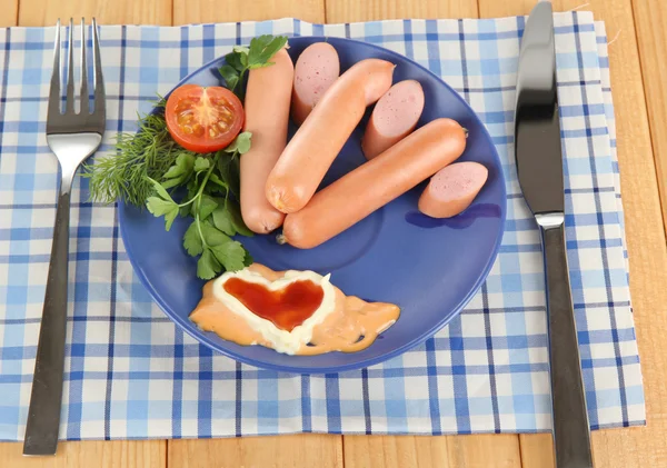 Sausage, greens, tomato on plate on wooden table — Stock Photo, Image