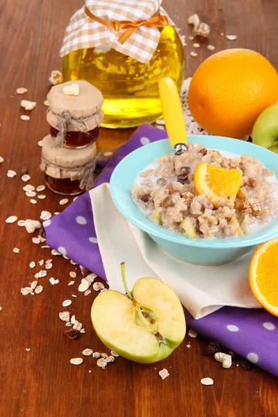 Useful oatmeal in bowl with fruit on wooden table close-up — Stock Photo, Image