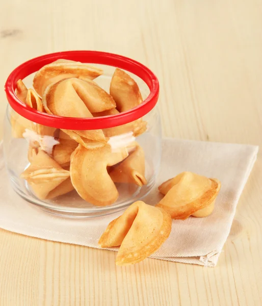 Fortune cookies in glass jar, on wooden table — Stock Photo, Image
