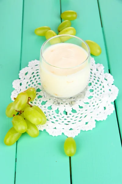 Delicious yogurt in glass with grapes on wooden table close-up — Stock Photo, Image