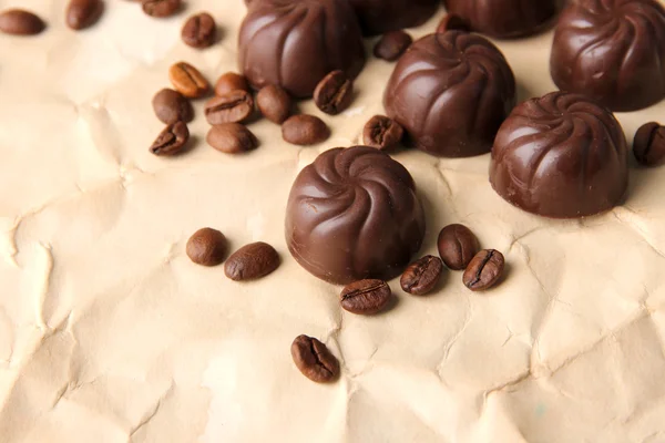 Chocolate candies and coffee beans, on beige paper background — Stock Photo, Image