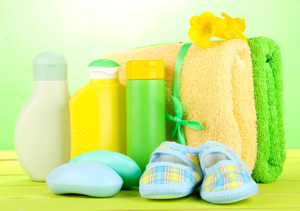 Cosméticos para bebés, jabón y toallas sobre mesa de madera, sobre fondo verde — Foto de Stock