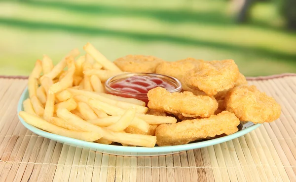 Fried chicken nuggets with french fries and sauce on table in park — Stock Photo, Image