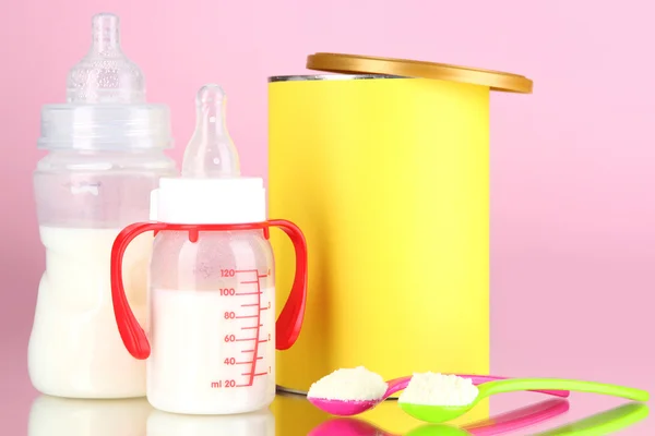 Bottles with milk and food for babies on pink background — Stock Photo, Image