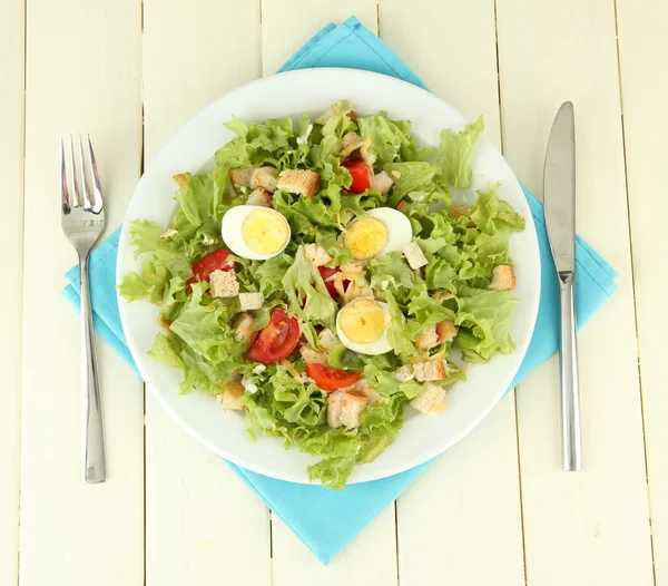 Caesar-Salat auf weißem Teller, auf farbigem Holzhintergrund — Stockfoto