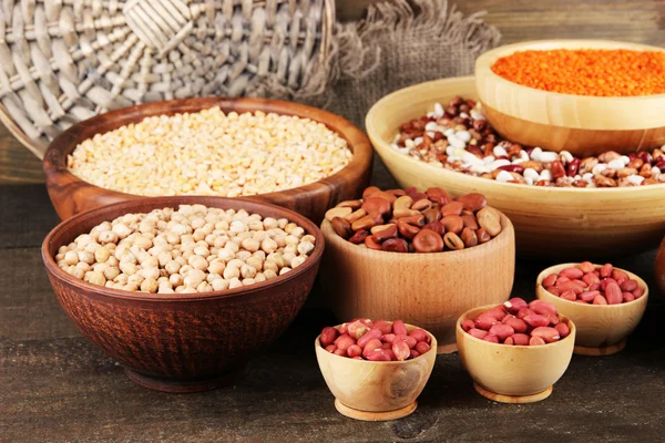 Different kinds of beans in bowls on wooden background — Stock Photo, Image