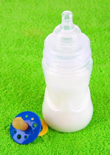 Botella para leche y pezón sobre fondo de toalla —  Fotos de Stock
