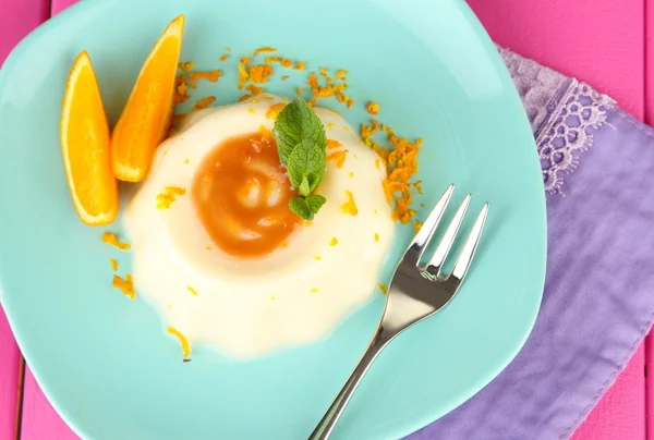 Panna cotta mit Orangenschale und Karamellsoße, auf farbigem Holzhintergrund — Stockfoto