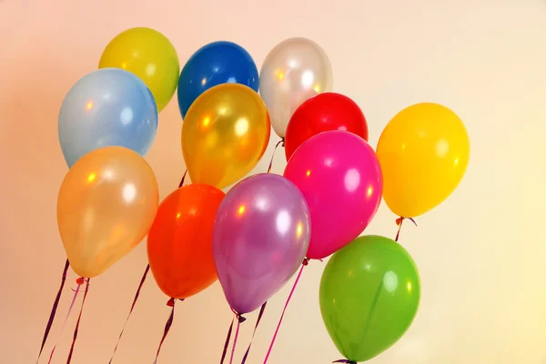 Viele helle Luftballons auf orangefarbenem Hintergrund — Stockfoto