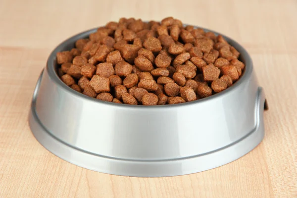 Comida seca para perros en un tazón sobre fondo de madera — Foto de Stock