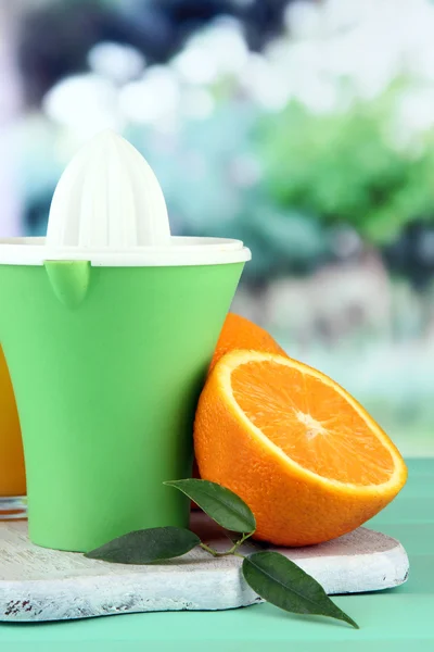 Prensa cítrica, vaso de jugo y naranjas maduras sobre mesa de madera verde — Foto de Stock