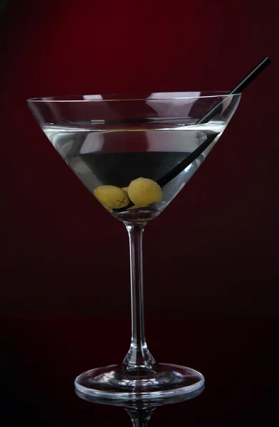 Martini glass with olives on dark red background — Stock Photo, Image