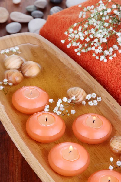 Beautiful candles in water on wooden table close-up — Stock Photo, Image