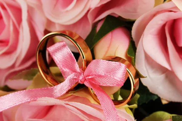 Anillos de boda atados con cinta sobre fondo rosa —  Fotos de Stock