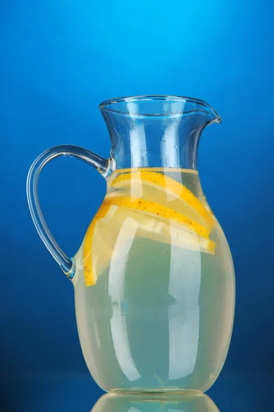 Lemonade in pitcher on blue background — Stock Photo, Image