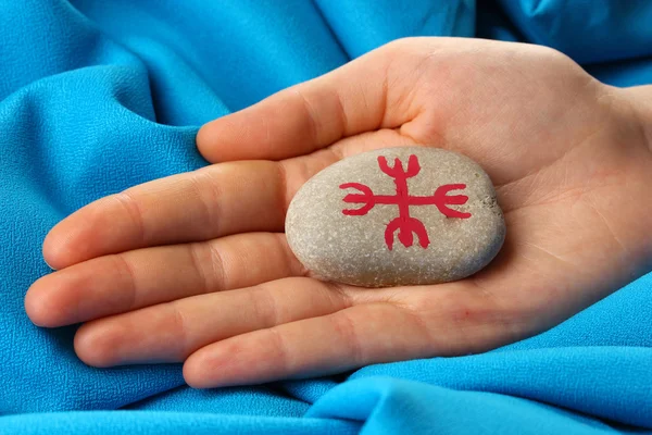 Fortune telling with symbols on stone in hand on blue fabric background — Stock Photo, Image