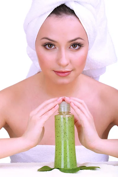 Beautiful young woman with towel on her head and bottle of cream with scrub isolated on white — Stock Photo, Image