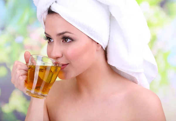 Piękna młoda kobieta z filiżanką herbaty ziołowej, na jasnym tle — Zdjęcie stockowe