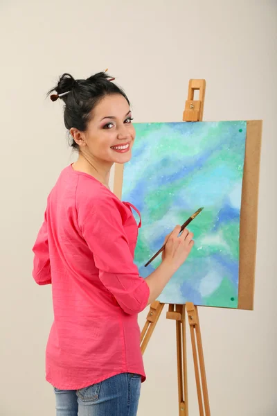 Beautiful young woman painter at work, on color background — Stock Photo, Image