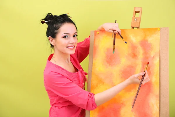 Mooie jonge vrouw schilder op het werk, op een achtergrond met kleur — Stockfoto
