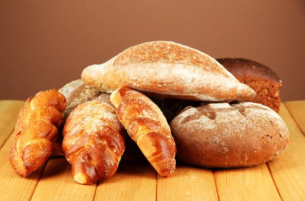 Samenstelling met brood en broodjes op houten tafel, op een achtergrond met kleur — Stockfoto