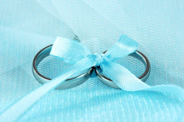 Snubní prsteny svázané stuhou na hadřík pozadí — Stock fotografie