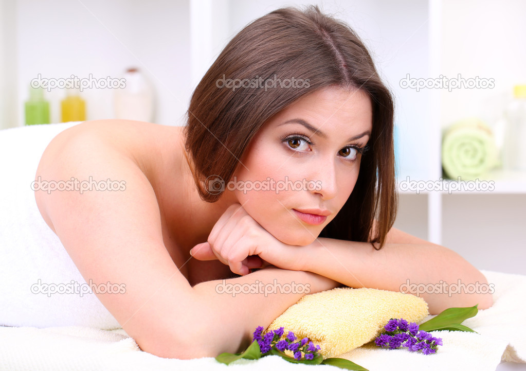 Beautiful young woman lying in spa salon close up