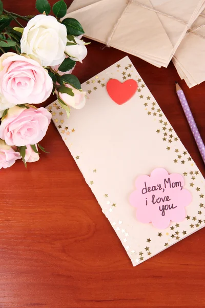 Writing letter of congratulations to mother's Day on wooden table close-up — Stock Photo, Image
