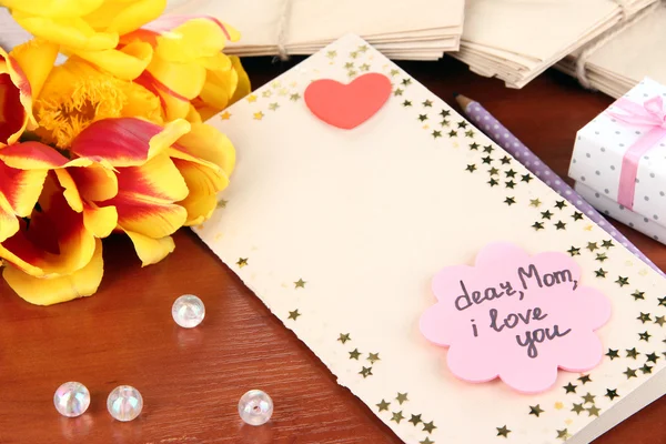 Carta de escrita de congratulações ao Dia de mãe em close-up de mesa de madeira — Fotografia de Stock