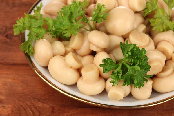 Marinated mushrooms in saucer on wooden table — Stock Photo, Image