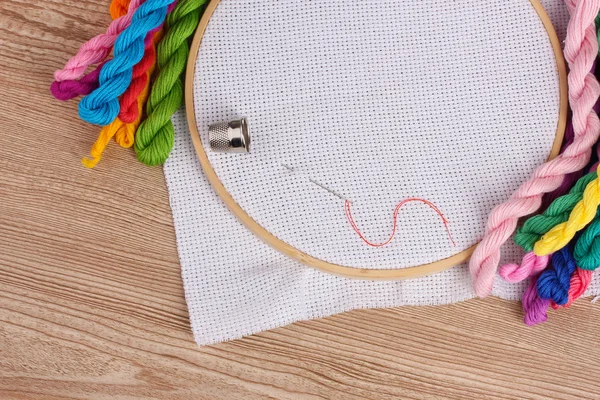 The embroidery hoop with canvas and bright sewing threads for embroidery in the table — Stock Photo, Image