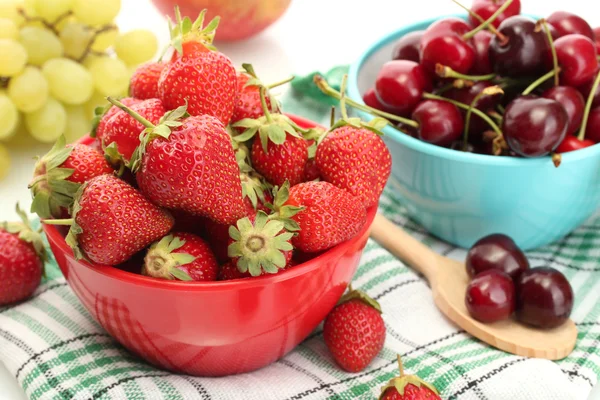 Ripe strawberries and cherry berries in bowls, grapes and apple close up — Stock Photo, Image