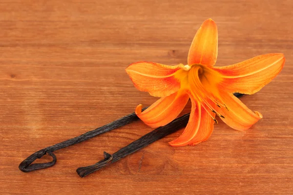 Casulos de baunilha com flor sobre fundo de madeira — Fotografia de Stock