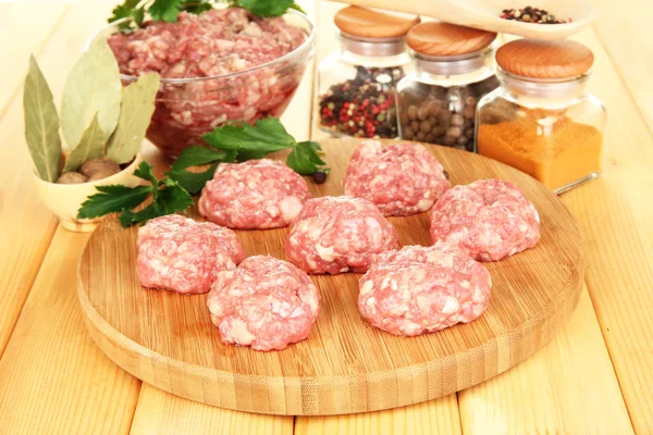 Raw meatballs with spices on wooden table — Stock Photo, Image