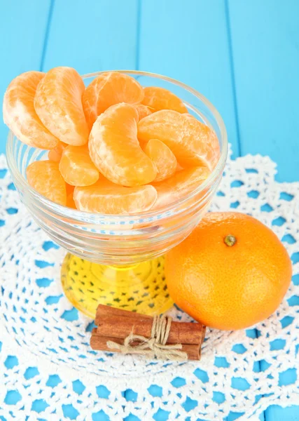 Sabrosas rebanadas de mandarina en tazón de vidrio sobre fondo azul —  Fotos de Stock